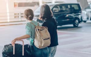 Two people with luggage looking for a shuttle at an airport