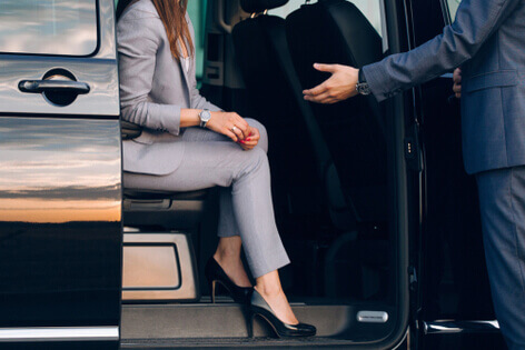 A driver helping a businessperson out of an executive vehicle 